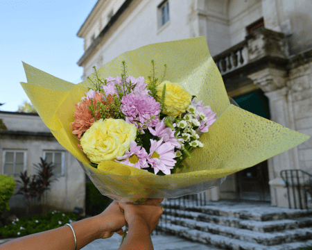Bright spring bouquet wrapped in yellow paper featuring roses, chrysanthemums and daisies